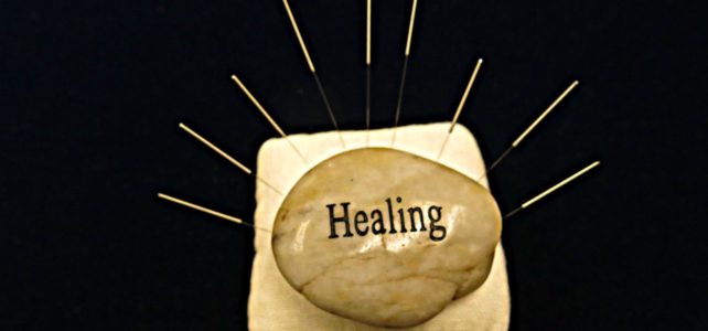 Healing stone surrounded by acupuncture needles